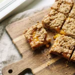 peach crumb bars recipe on wooden cutting board